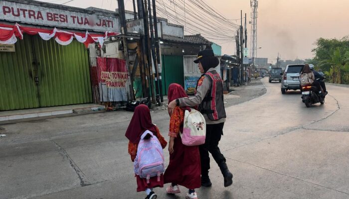 Humanis! Kapolsek Telukjambe Barat Gandeng Bocah Sekolah Menyeberang di Jalan Raya Badami-Loji